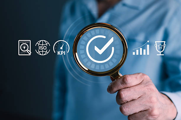 istock Businessman with magnifying glass inspecting quality control, ISO compliance, KPI metrics, and performance analysis for business success and certification 2245091342