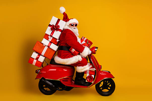istock Santa on a red scooter loaded with gifts smiles in bright studio setting for Christmas adventure and holiday shopping vibe 2245092907