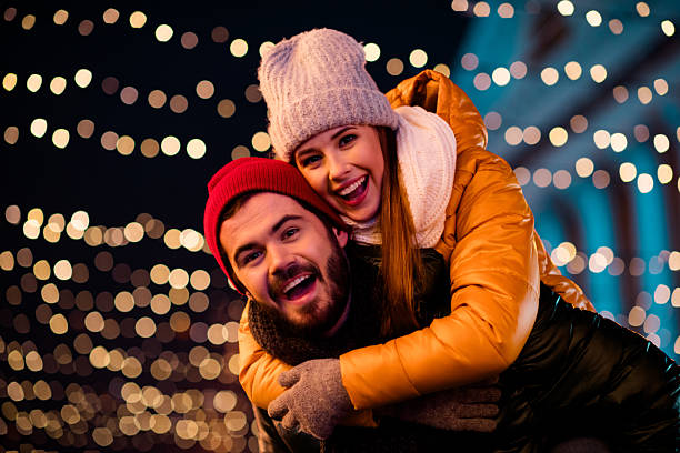 istock Joyful couple outdoors under festive lights share a playful moment creating a warm Christmas scene for family friends and love in a winter city 2245092950
