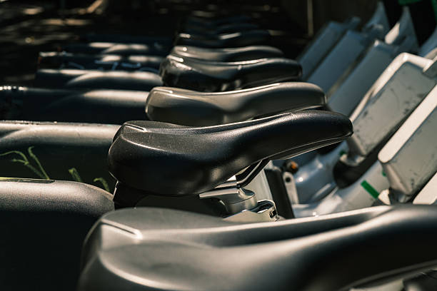 A row of black leather bicycle seats. Focus on the second seat.