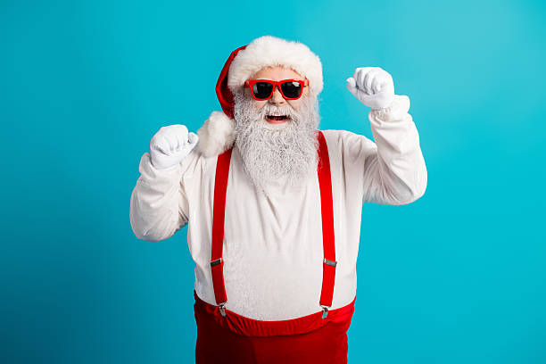 istock Santa in red suspenders and a white suit dances with joy on a bright blue studio background perfect for Christmas holiday campaigns 2245098619