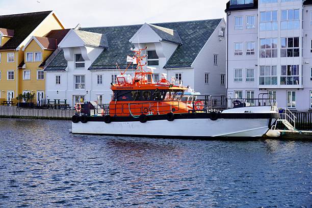 Floroe, Norway – March 21, 2025: A vibrant orange pilot vessel Kvanhovden moored in Floroe harbour.