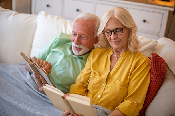 istock Mature couple reading books together relaxing on couch 2245108457
