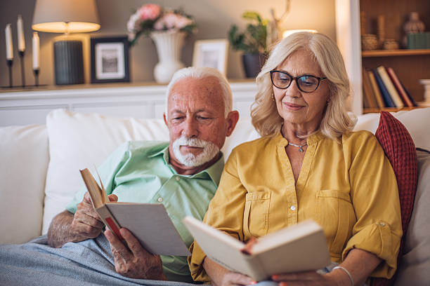 istock Senior couple relaxing on sofa reading books together 2245108509