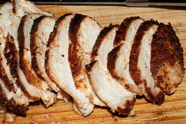 istock Thinly sliced seasoned cooked chicken brest on chopping board 2245110439