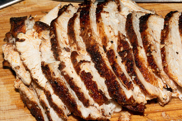 istock Thinly sliced seasoned cooked chicken brest on chopping board 2245110461
