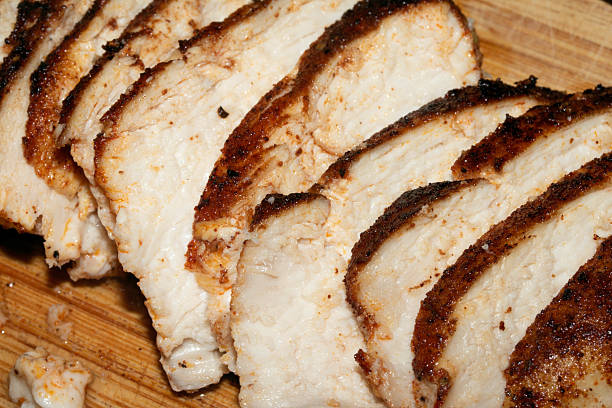 istock Thinly sliced seasoned cooked chicken brest on chopping board 2245110509
