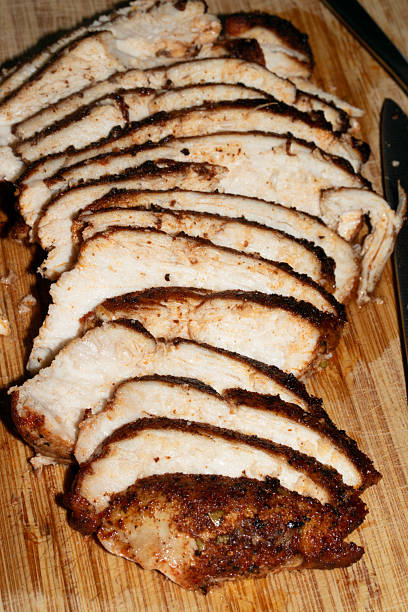istock Thinly sliced seasoned cooked chicken brest on chopping board 2245110615
