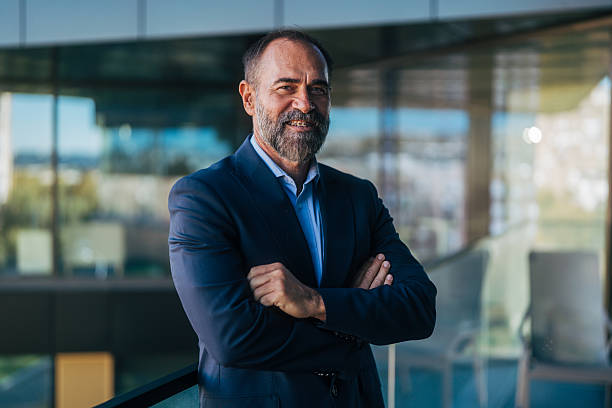 istock Confident mature businessman posing with corporate building background 2245110716