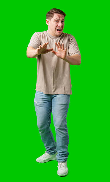 istock Man expressing fear while standing against a bright green background 2245113844