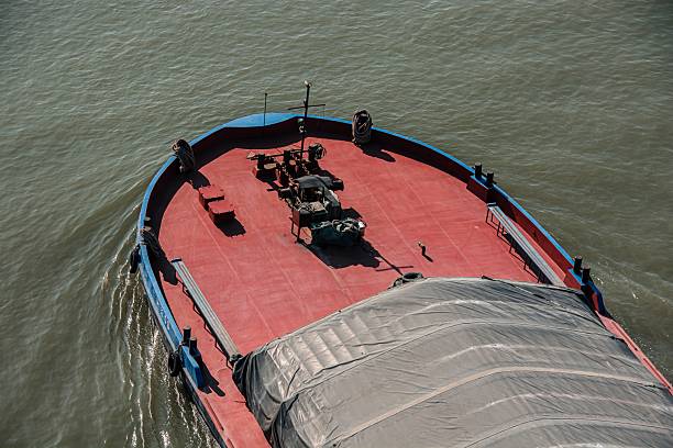 Wuhan, China – November 02, 2025: Aerial view of a red and blue cargo boat navigating through calm waters under clear skies.