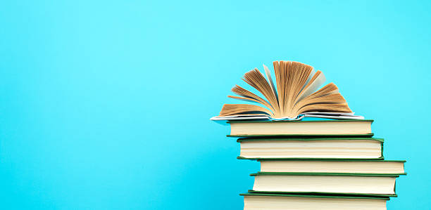 istock Open book, hardback books on wooden table, on a blue background. Back to school. Copy space for text. Education background. panorama, banner. 2245115595