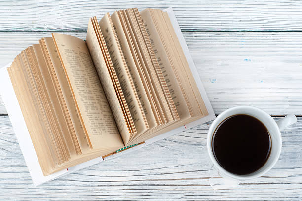 istock Open book, coffee cup and snack on wooden table background. 2245115665