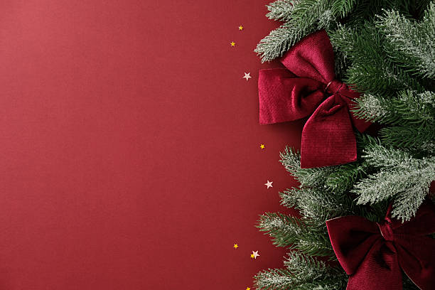 istock Christmas card design. Red background with pine branches and velvet bows on right side, decorated with gold and silver star confetti 2245118178