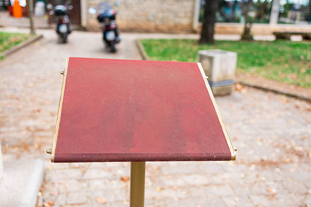 Empty red information stand in outdoor setting. Urban signage, public space infrastructure, and blank communication surface