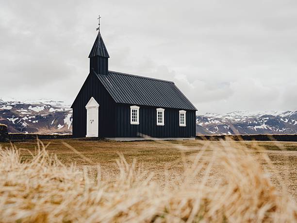 istock Black church with snowy mountain backdrop in Iceland. 2245121065