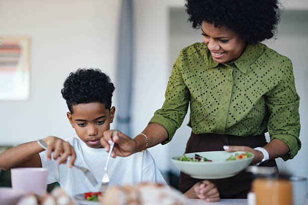 istock Mother Helps Son During Breakfast At Modern Apartment Kitchen Table Together 2245126370