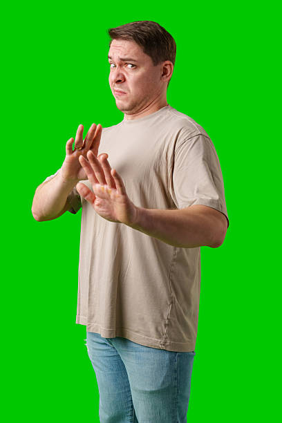 istock A man with a neutral expression gestures defensively against a bright green background 2245127933