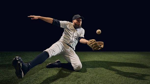 istock Baseball player sliding low fielding rolling ball with outstretched glove on turf 2245128757