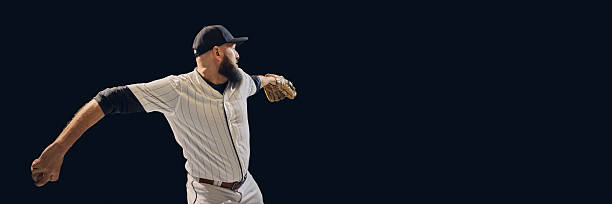 A baseball player photographed from the back holding a glove, standing on a green field during a game. The image highlights the sport, teamwork, and the field's texture.