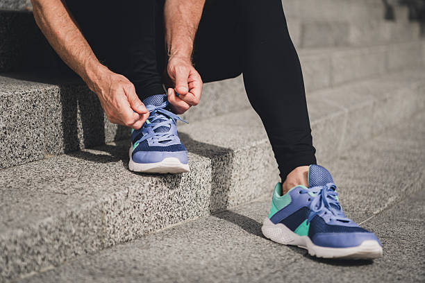 istock Man tying sneaker on outdoor steps in urban park setting during morning workout with athletic shoes for fitness and city lifestyle 2245130051