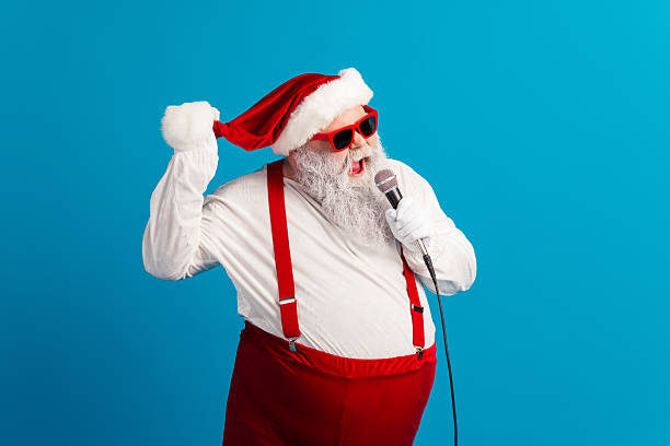 istock Santa singer in red suit with hat suspenders beard and microphone performs festive act against blue background 2245130765