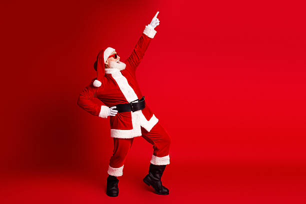 istock Santa in red costume with hat beard strikes dynamic pose bold red background celebrating Christmas fun family and holiday joy festive seasonal scene 2245134690