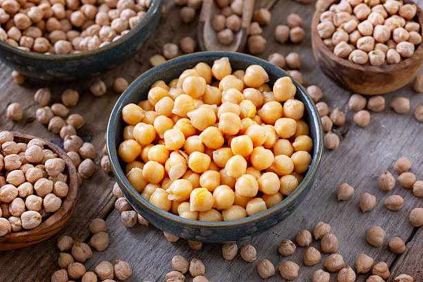 Cooked and raw chick-peas on wooden table