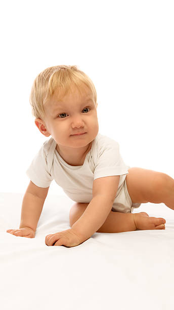 istock Happy baby crawling forward smiling with playful energy on bright soft white bedding 2245136025