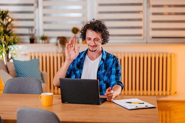 istock Mid-Adult Man Having A Work Video Call On A Laptop While Sitting At The Kitchen Table At Home 2245138595
