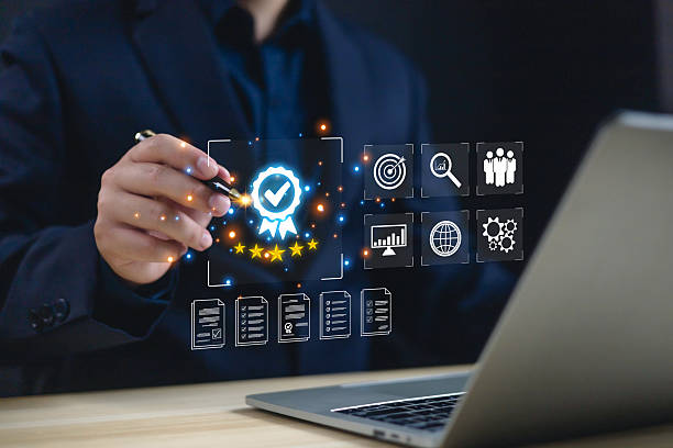 istock Businessman using digital pen with hologram quality assurance certification icon and five stars rating on laptop screen, concept of standard approval, customer satisfaction, and business excellence. 2245138795