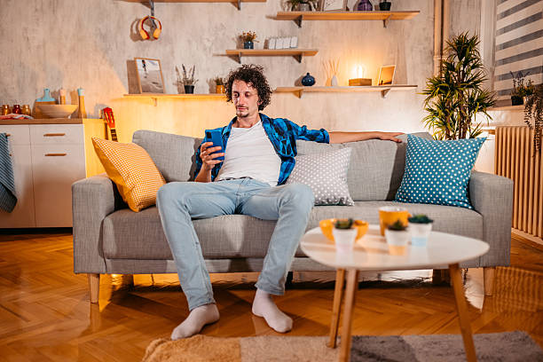 istock Mid-Adult Man Using Phone On The Sofa At Home 2245139113