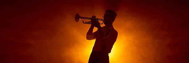 istock Trumpet player silhouette against warm concert lighting background. Banner 2245141003