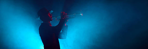 Saxophone player silhouette in yellow light with smoky stage background. Banner