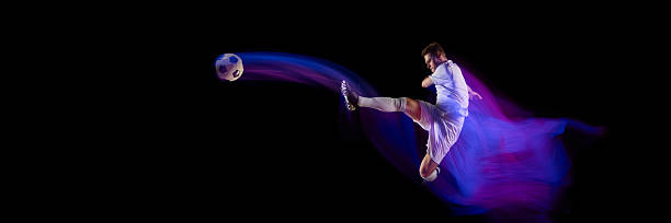 istock Football player performing kick with ball trajectory motion blur. Banner 2245142194