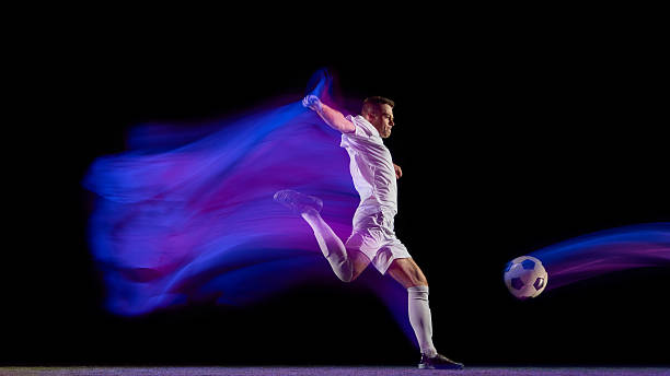 istock Soccer player kicking ball with dynamic blue and purple motion trail 2245142198