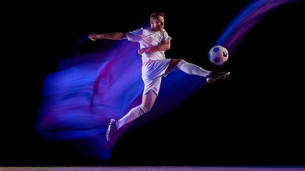 istock Soccer player jumping and kicking ball with abstract color trail 2245142203