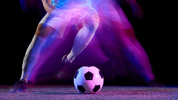 istock Soccer player dribbling ball in motion blur under violet neon lights 2245142204