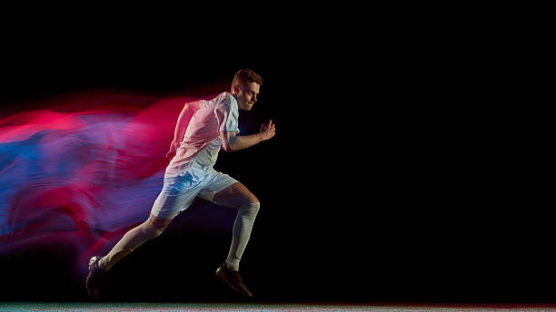 istock Football player running fast with glowing red and blue motion blur in dynamic action 2245142218