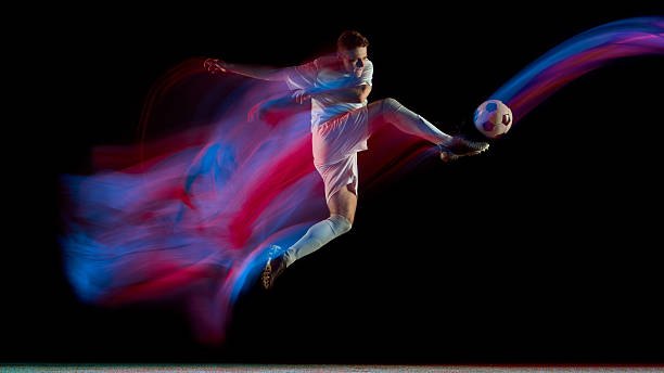 istock Soccer player performing dynamic kick with red and blue motion trail on dark background 2245142221