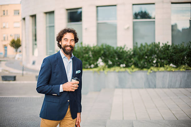 istock Smiling businessman holding coffee outdoors in city 2245142257
