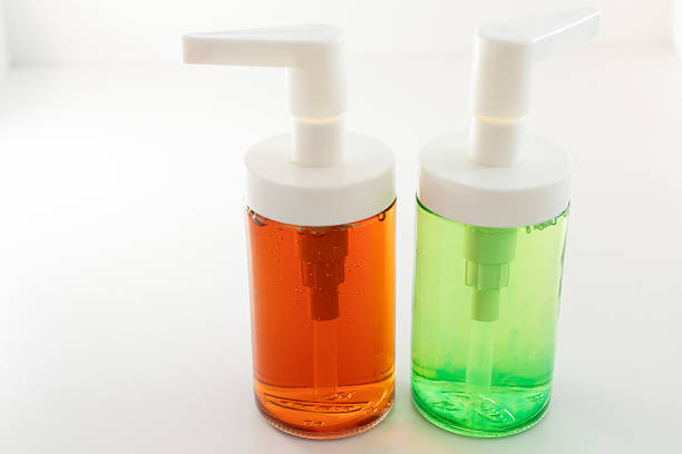 Soap dispensers with orange and green liquid on a white background