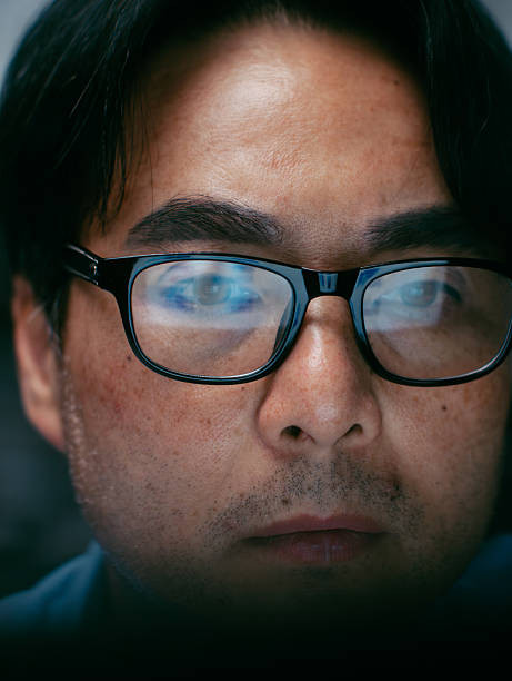 istock Close up of Businessman wearing Glasses with Business report graph and chart data reflection in glasses. Male Business Manager watching computer display in office at night. 2245147021