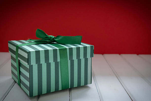 Christmas or birthday gift box on white wooden table with red background