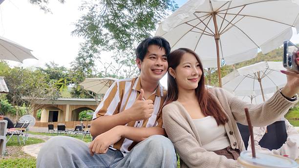 istock A couple is sitting under an umbrella, taking a selfie 2245148811