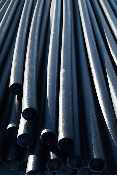 istock Stacked black plastic pipes on the construction site, highlighting their smooth texture and cylindrical shape, create an industrial atmosphere and demonstrate storage techniques. 2245150212