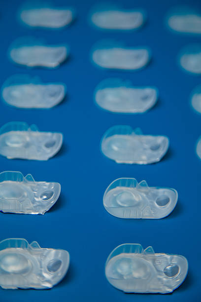 Side view horizontal photo pattern disposable containers with contact lenses lying in a row at the same distance, front in focus on a blue background. Concept of vision correction, ophthalmology, myopia and hyperopia