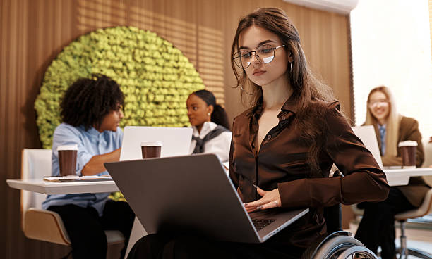 istock Confident woman working on laptop in modern inclusive office, using wheelchair 2245154525