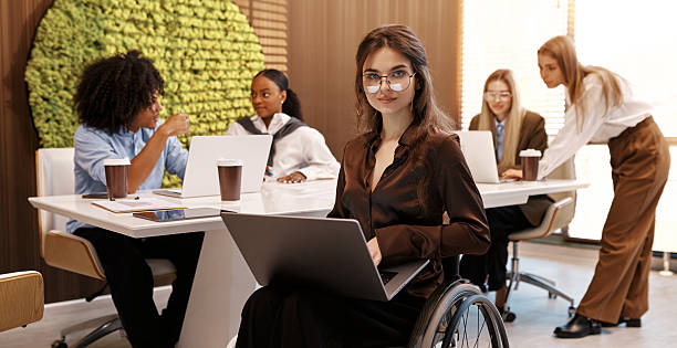 istock Confident woman working on laptop in modern inclusive office, using wheelchair 2245154533