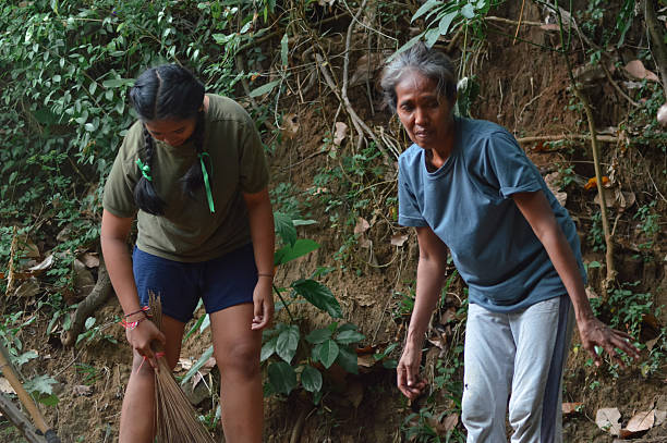 istock Mother searching for fallen cashew fruits while daughter sweeps yard 2245156042
